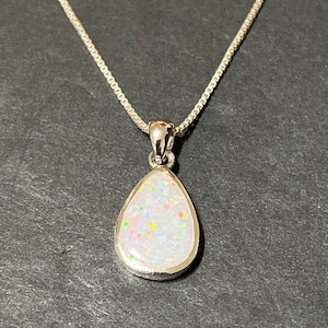 May include: A silver chain necklace with a teardrop-shaped pendant featuring a white opal with iridescent flecks.