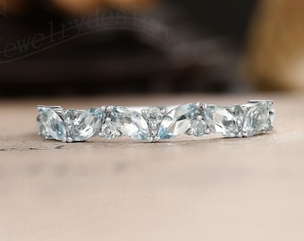 May include: A delicate silver band with a row of marquise-shaped aquamarine gemstones.