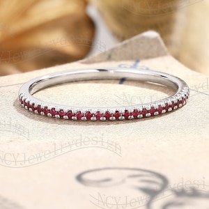May include: A thin silver band with a row of small red gemstones.