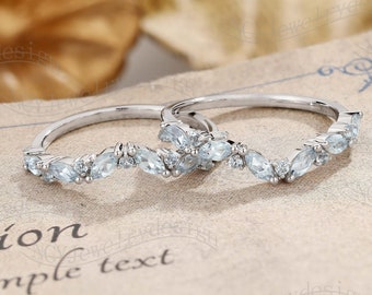 May include: Two delicate silver rings with a row of marquise-shaped blue gemstones. The rings are set on a white background.