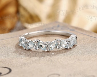 May include: A delicate silver band with a row of marquise-shaped aquamarine gemstones set in a curved design.