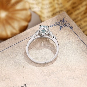 May include: A silver engagement ring with a light blue gemstone in the center and smaller gemstones on the band.