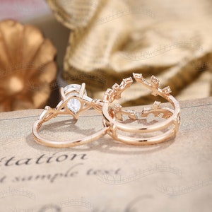 May include: A set of two rose gold rings with a pear-shaped diamond in the center of the larger ring. The smaller ring has a delicate leaf design.