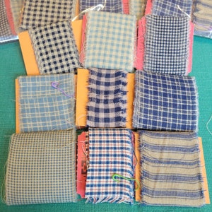 May include: Assortment of fabric scraps in various plaid patterns, including blue, white, and tan. The fabric scraps are arranged in a grid pattern on a green surface.