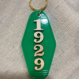 May include: Green motel key chain with a gold key ring and the number 1929 printed in white on the front.