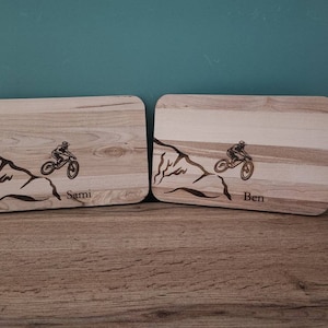 Könnte beinhalten: Zwei Holz-Schneidebretter mit lasergravierten Mountainbike-Designs und personalisierten Namen "Sami" und "Ben".