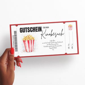 May include: Red and white ticket-shaped gift certificate with the text "GUTSCHEIN F&Uuml;R EINEN Kinobesuch" and a drawing of a bucket of popcorn. The text below the drawing reads "Lieber Max, es wird mal wieder Zeit f&uuml;r einen Kinobesuch mit allem Drum und Dran. Du darfst nat&uuml;rlich den Film aussuchen. Happy Birthday! Tim". The text at the bottom right corner reads "F&Uuml;R Max VON Tim".