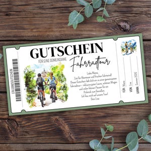Op de afbeelding: Een groen en wit cadeau-certificaat in ticketstijl met de woorden "GUTSCHEIN" en "Fahrradtour" erop gedrukt. Het certificaat toont een illustratie van twee mensen die fietsen en tekst in het Duits. Het certificaat ligt op een houten oppervlak.