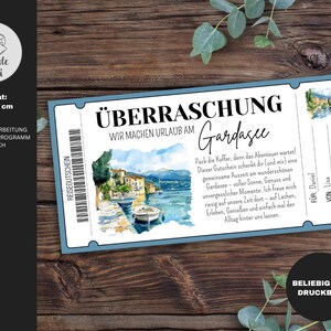 以下が含まれることがあります： 「&Uuml;BERRASCHUNG」と「Gardasee」の文字が入った、青と白のチケット風ギフト券。湖畔の町の水彩イラストと「WIR MACHEN URLAUB AM」の文字が入っています。サイズは10 x 20 cmです。