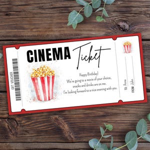 Peut inclure: Un billet de cinéma rouge et blanc avec une illustration aquarelle d'un seau de pop-corn. Le texte sur le billet indique "CINEMA Ticket" et "Joyeux anniversaire ! On va au cinéma de votre choix, les snacks et les boissons sont pour moi. J'ai hâte de passer une agréable soirée avec vous." Le billet comprend également le texte "À : Anna" et "De : John".