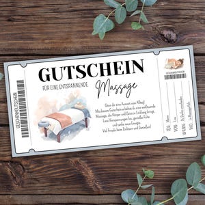 Può includere: Un buono regalo per un massaggio, con la parola "GUTSCHEIN" in grandi caratteri. Il buono include testo in tedesco e un'illustrazione di un lettino da massaggio. Lo sfondo è una superficie di legno.