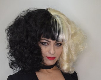 May include: A woman with half black and half blonde curly hair, wearing a black choker necklace and a black blazer.