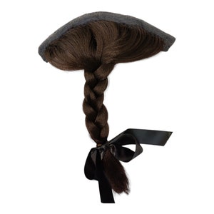 May include: A brown hair extension with a black ribbon tied at the end. The extension is braided and has a black mesh clip at the top.