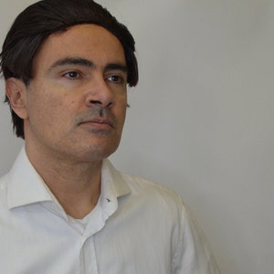 Puede incluir: Un hombre con el pelo corto y castaño oscuro que lleva una camisa blanca con cuello. Está mirando hacia la derecha del encuadre.