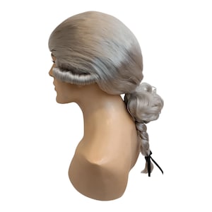 May include: A light gray wig styled in the fashion of the 18th century, featuring a powdered look. The wig is mounted on a mannequin head, showcasing the side profile with a braided ponytail and a bow.