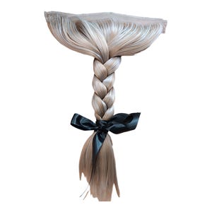May include: A blonde braided hair extension with a black ribbon tied at the end.