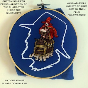 May include: A blue embroidery hoop with a white outline of a person sitting on a treasure chest. The person is wearing a red hat and robe. The text "CUSTOMISBLE FOR PERSONALISATION OF THE CHARACTER INSIDE THE SILHOUETTE" is at the top of the hoop. The text "AVAILABLE IN A VARIETY OF SIZES (5CM TO 15CM PLUS PILLOWCASES)" is at the top right of the hoop. The text "ANY QUESTIONS PLEASE CONTACT ME" is at the bottom of the hoop.