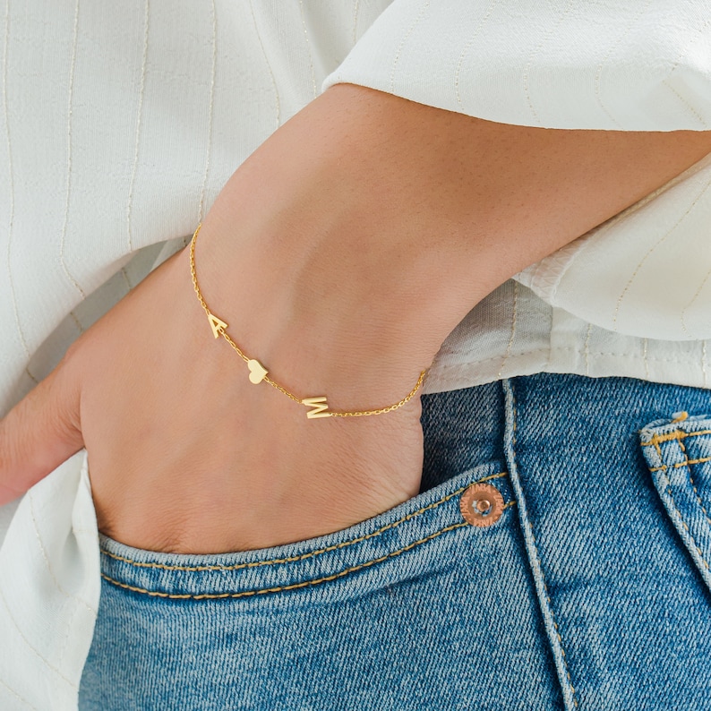 May include: A gold chain bracelet with the letters A and M and a heart charm.