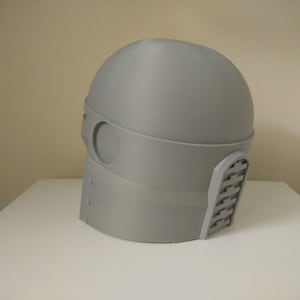 May include: A grey 3D printed helmet with a visor and a textured design on the side.