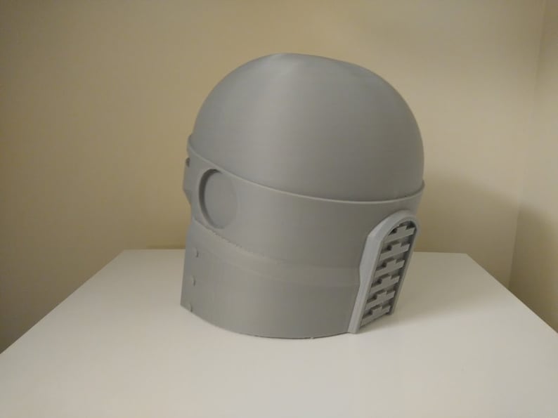 May include: A grey 3D printed helmet with a visor and a textured design on the side.