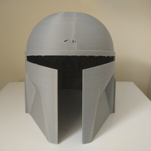 May include: A grey 3D printed helmet with a visor and a textured surface.