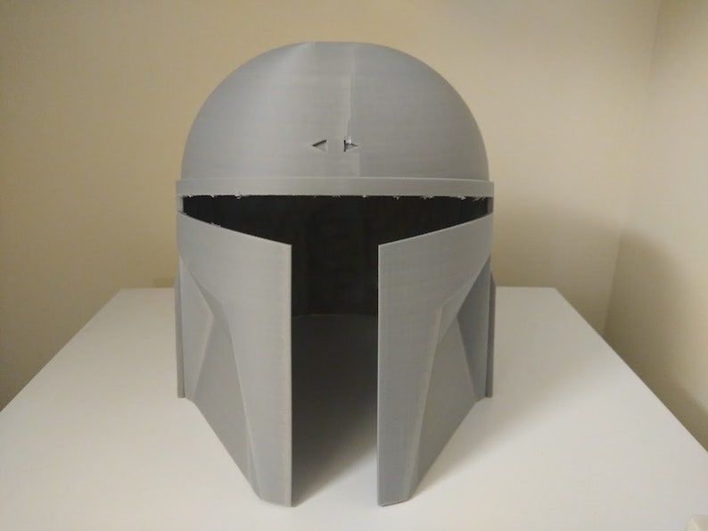 May include: A grey 3D printed helmet with a visor and a textured surface.