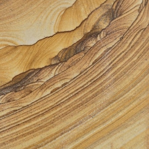 May include: A close-up view of a natural stone surface featuring intricate, flowing layers of tan, beige, and dark brown mineral deposits. The pattern displays organic, curved lines that create a textured, layered appearance across the entire surface.