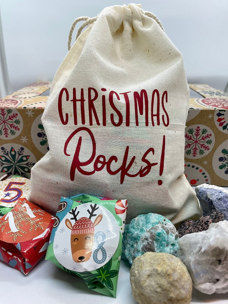 May include: A white canvas bag with red text that says "Christmas Rocks!" The bag is filled with wrapped gifts and colorful rocks.
