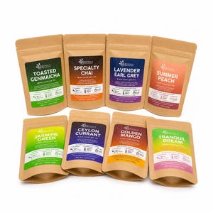 May include: Eight brown kraft paper pouches of Bathala Botanicals loose leaf tea arranged in two rows. Each pouch features a colorful label with the tea name, including Toasted Genmaicha, Specialty Chai, Lavender Earl Grey, Summer Peach, Jasmine Green, Ceylon Currant, Golden Mango, and Tranquil Dream, with net weights listed in ounces.