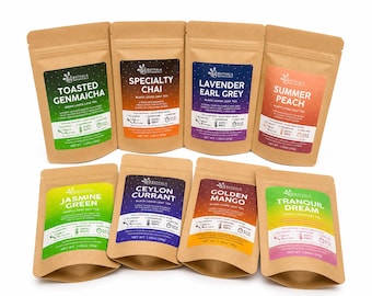 May include: Eight brown kraft paper pouches of Bathala Botanicals loose leaf tea arranged in two rows. Each pouch features a colourful label with the tea name, including Toasted Genmaicha, Specialty Chai, Lavender Earl Grey, Summer Peach, Jasmine Green, Ceylon Currant, Golden Mango, and Tranquil Dream, with net weights listed in grams.