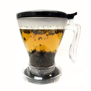 May include: A clear glass tea infuser with a black lid and a clear handle. The infuser is filled with loose leaf tea and water. The infuser is sitting on a black base.
