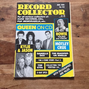 May include: A magazine cover for Record Collector, a publication for collectors of rare records, CDs, and pop memorabilia. The cover features Queen, Kylie Minogue and Jason Donovan, Bowie, Motley Crue, and Danielle Dax. The magazine is from November 1989.