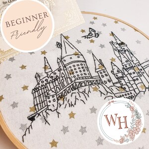 May include: Embroidered hoop art featuring a black line drawing of Hogwarts castle on a white fabric background with gold and silver glitter stars. The text "BEGINNER FRIENDLY" is in a pink circle at the top left of the image. The text "WH" is in a circle with floral accents at the bottom right of the image.