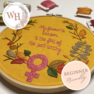 May include: A yellow embroidery hoop with a pink female symbol, surrounded by brown branches and leaves. The text "My favorite season is the fall of the patriarchy" is embroidered in pink thread. The hoop is labeled "Beginner Friendly".