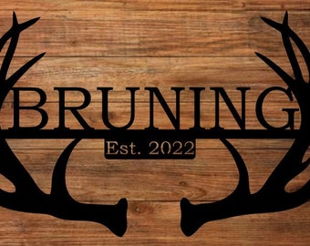 May include: Black metal silhouette of a pair of antlers with the name "BRUNING" and the text "Est. 2022" in the center.