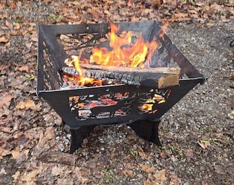 May include: A black metal fire pit with a deer design. The fire pit is on a gravel surface with fallen leaves. The fire pit has a fire burning inside.