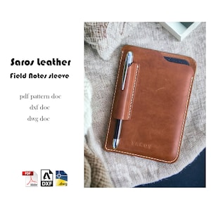May include: A brown leather sleeve for a Field Notes notebook with a pen holder. The sleeve has the word "SAROS" embossed on the front. The sleeve is on a beige fabric background. The image includes the text "Saros leather Field Notes sleeve pdf pattern doc dxf doc dwg doc".