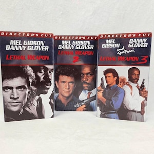 May include: Three VHS tapes of the "Lethal Weapon" movie series. The tapes feature Mel Gibson and Danny Glover. The first tape is labeled "Lethal Weapon", the second "Lethal Weapon 2", and the third "Lethal Weapon 3". The text "Director's Cut" is at the top of each tape.