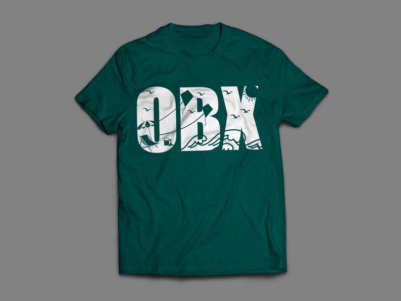 May include: A teal green t-shirt featuring a white graphic of the word "OBX" with beach-themed imagery inside the letters.
