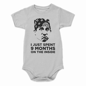 May include: A gray baby onesie with a black and white image of a man wearing a bandana and the text "I just spent 9 months on the inside."