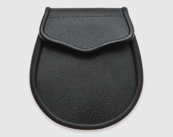 May include: A black leather sporran with a flap closure. The sporran is a traditional Scottish accessory worn as part of a kilt.