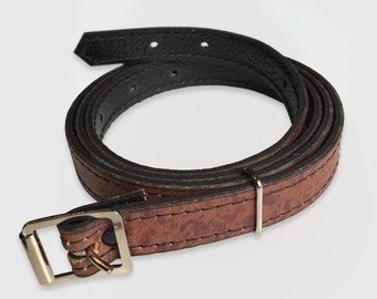 May include: A brown leather strap with a silver buckle and a black leather strap underneath.