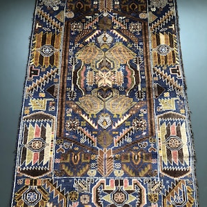 May include: A blue and brown patterned rug with intricate geometric designs. The rug has a fringe border and is made of wool.