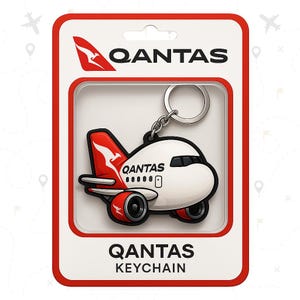 以下が含まれることがあります： 銀色のキーリングが付いた赤と白のカンタス航空機のキーホルダー。キーホルダーには、カンタスのロゴと「QANTAS KEYCHAIN」という文字が書かれたアニメーションの飛行機が描かれています。