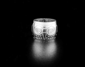 May include: Silver ring with an owl design. The owl's eyes are large and round, and its beak is pointed. The ring is a simple band with a smooth finish.