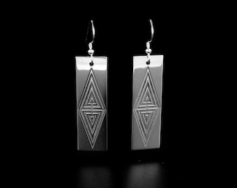 May include: A pair of silver earrings with a geometric design. The earrings are rectangular in shape and have a silver hook.
