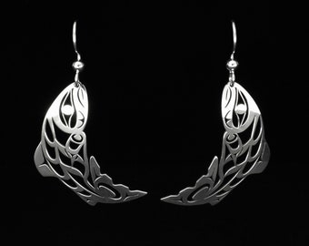 May include: A pair of silver earrings shaped like stylized salmon, with intricate details and a dangling design.