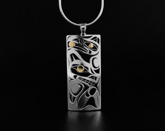 May include: A silver pendant with a rectangular shape and a detailed Native American design. The pendant features a stylized animal motif with gold-colored accents. It hangs from a silver chain against a black background.