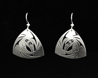 May include: A pair of silver earrings with a triangular shape and a detailed design of a stylized bird and fish. The earrings are made of metal and have a polished finish.