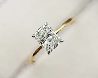 May include: A gold engagement ring with a large, clear, rectangular-shaped diamond.